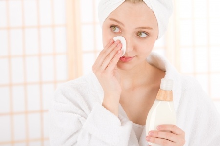 woman cleaning her face with a cotton pad