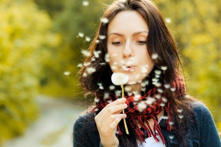 woman outside blowing a dandelion flower