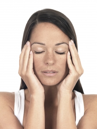 woman with headache holding sides of head