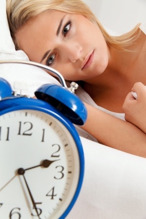 woman in bed looking at a clock