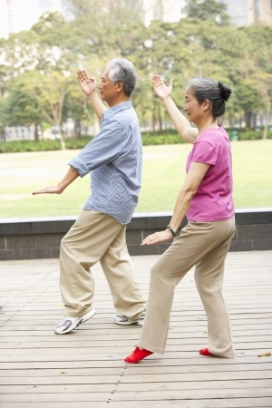 man and women doing tai chi in a park