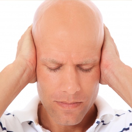 man holding ears due to tinnitus